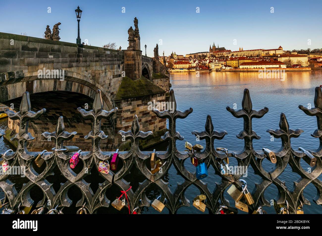 El amor se bloquea en las barandillas junto al río Vltava, el puente de Carlos y el castillo más allá. Praga República Checa Europa Foto de stock