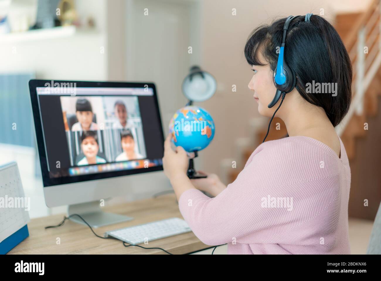 Profesora asiática enseñando geografía a través de videoconferencia e-learning y alegre estudiante de escuela primaria mirando Globe, Homeschooling y dist Foto de stock