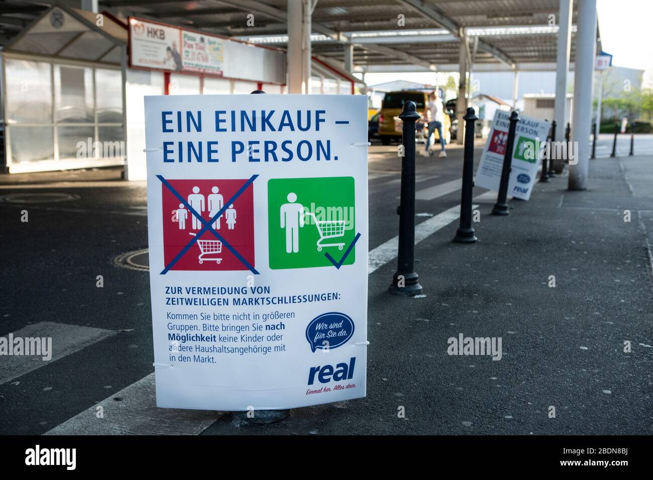Wegen der Corona-Pandemie gibt es vorgeschriebene Regeln, die beim Einkauf beachtet werden müssen. Das Kaufhaus REAL en Neuss sombrero Plakate vor dem eing Foto de stock