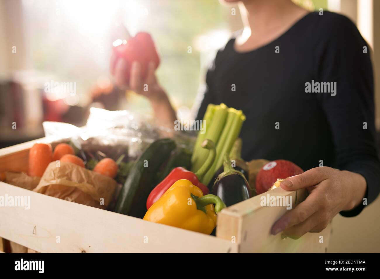Una mujer recibe una entrega de caja de verduras en una casa residencial en Guildford Surrey, Reino Unido el miércoles, abril. 8, 2020. Fotógrafo: Jason Alden Foto de stock