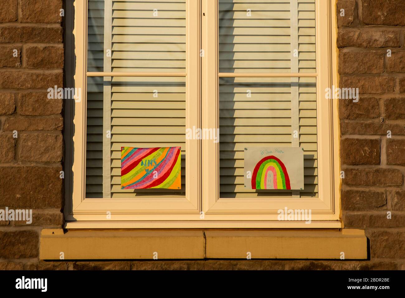 Obras de arte arcoiris para niños que apoyan el NHS durante el brote de coronavirus en la ventana de una casa, abril de 2020. Foto de stock