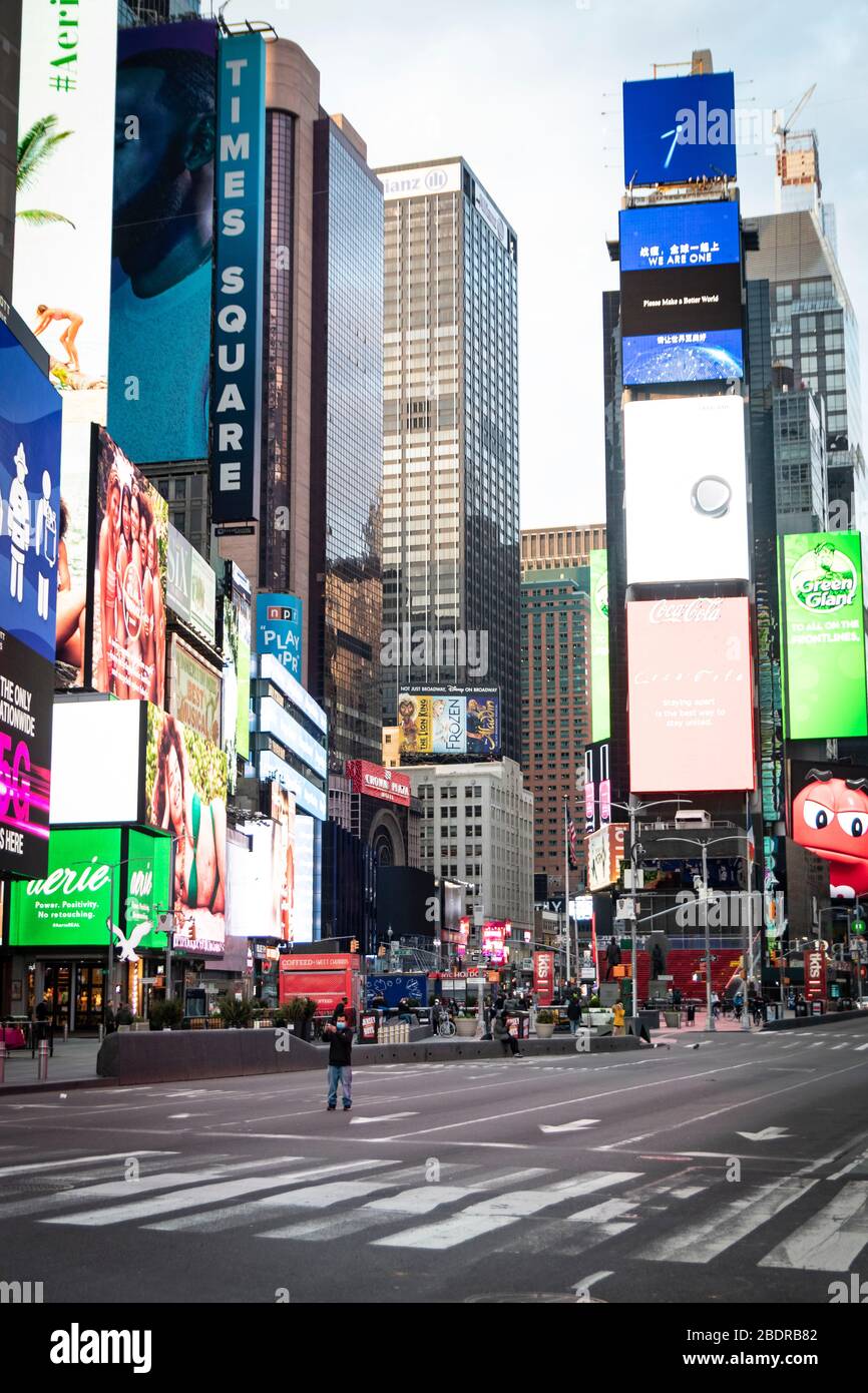 Un hombre se encuentra en medio de Times Square, vacío y vacío de turistas; como las empresas han sido cerradas para evitar la propagación de COVID-19. Foto de stock