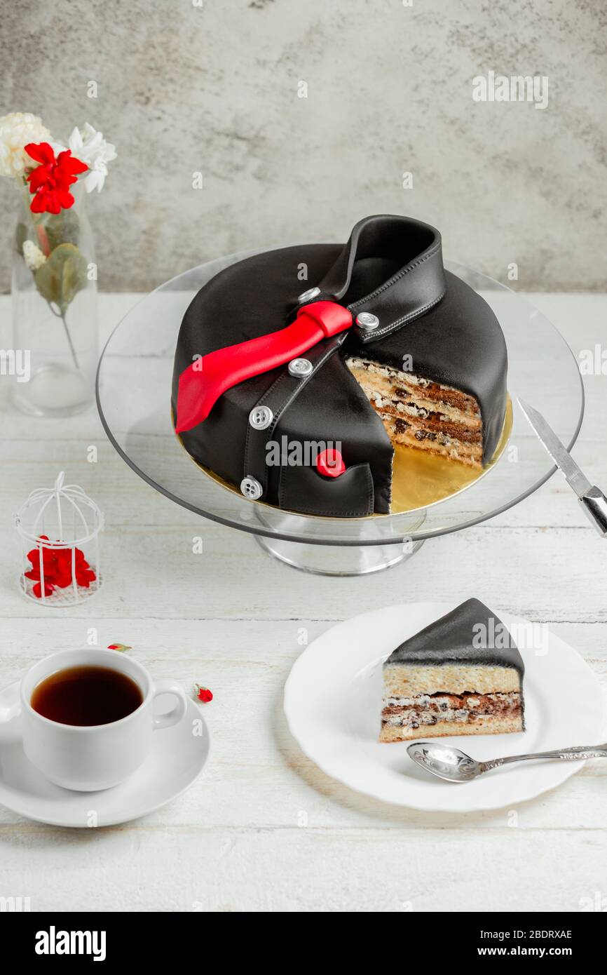 pastel redondo con piezas de chocolate en forma de camisa de hombre negro  con corbata roja Fotografía de stock - Alamy