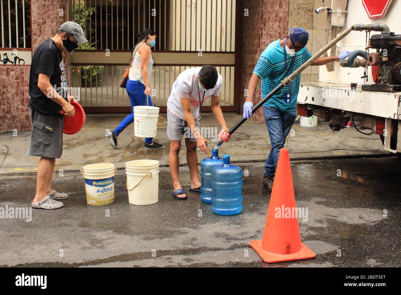 Caracas, Venezuela 4 de abril de 2020: Las personas llenan los contenedores con agua de la entrega de camiones cisterna por los principales municipios durante la cuarentena de COVID-19 Foto de stock
