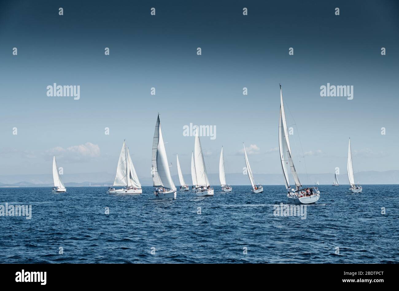 La carrera de veleros, una regata de vela, reflejo de velas en el agua, intensa competencia, el número de barcos es en popa, colores brillantes, la isla está en Foto de stock