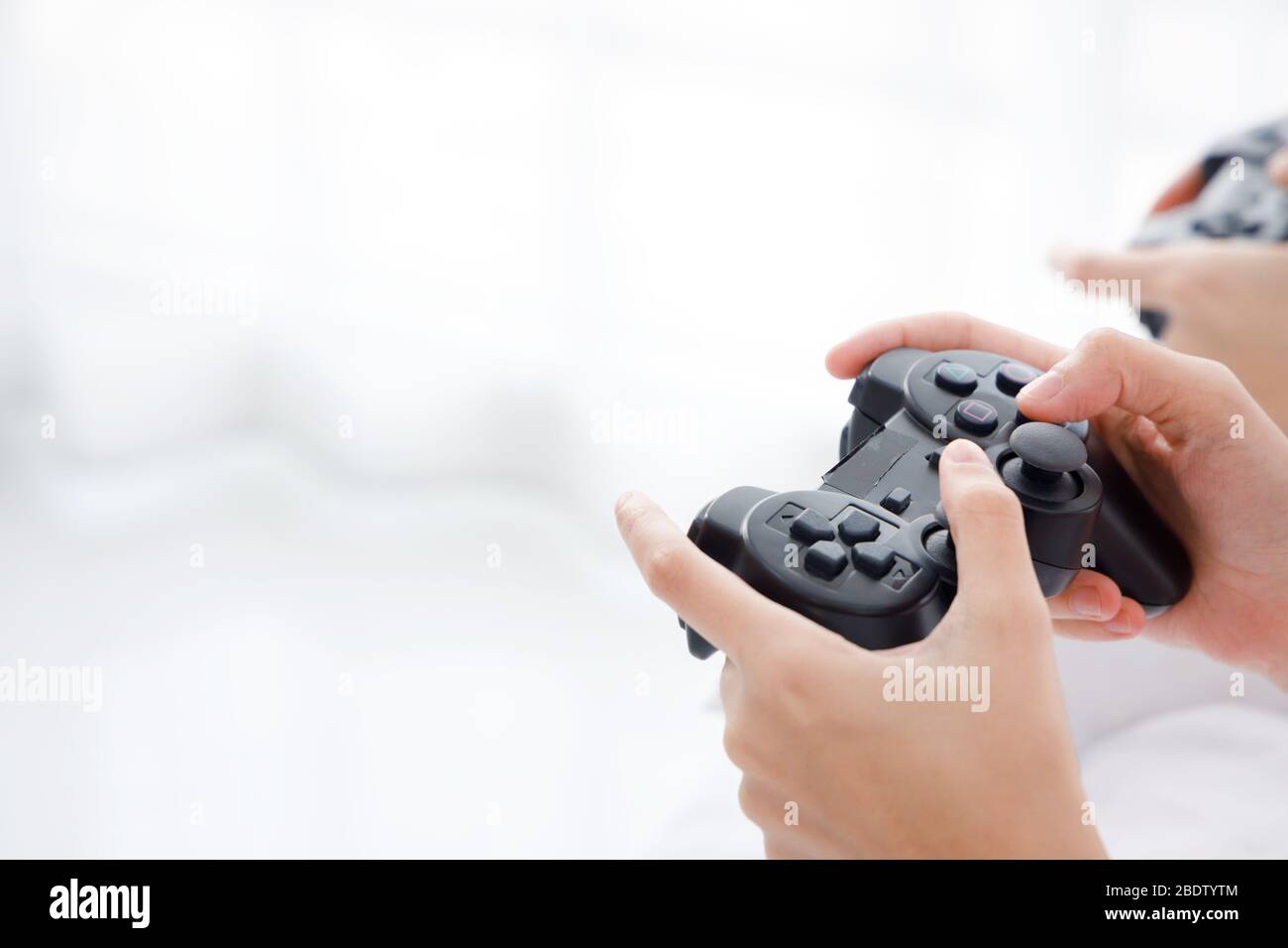 Primer plano mano sosteniendo el mando de juego inalámbrico negro con espacio de copia en el lado izquierdo. Foto de stock