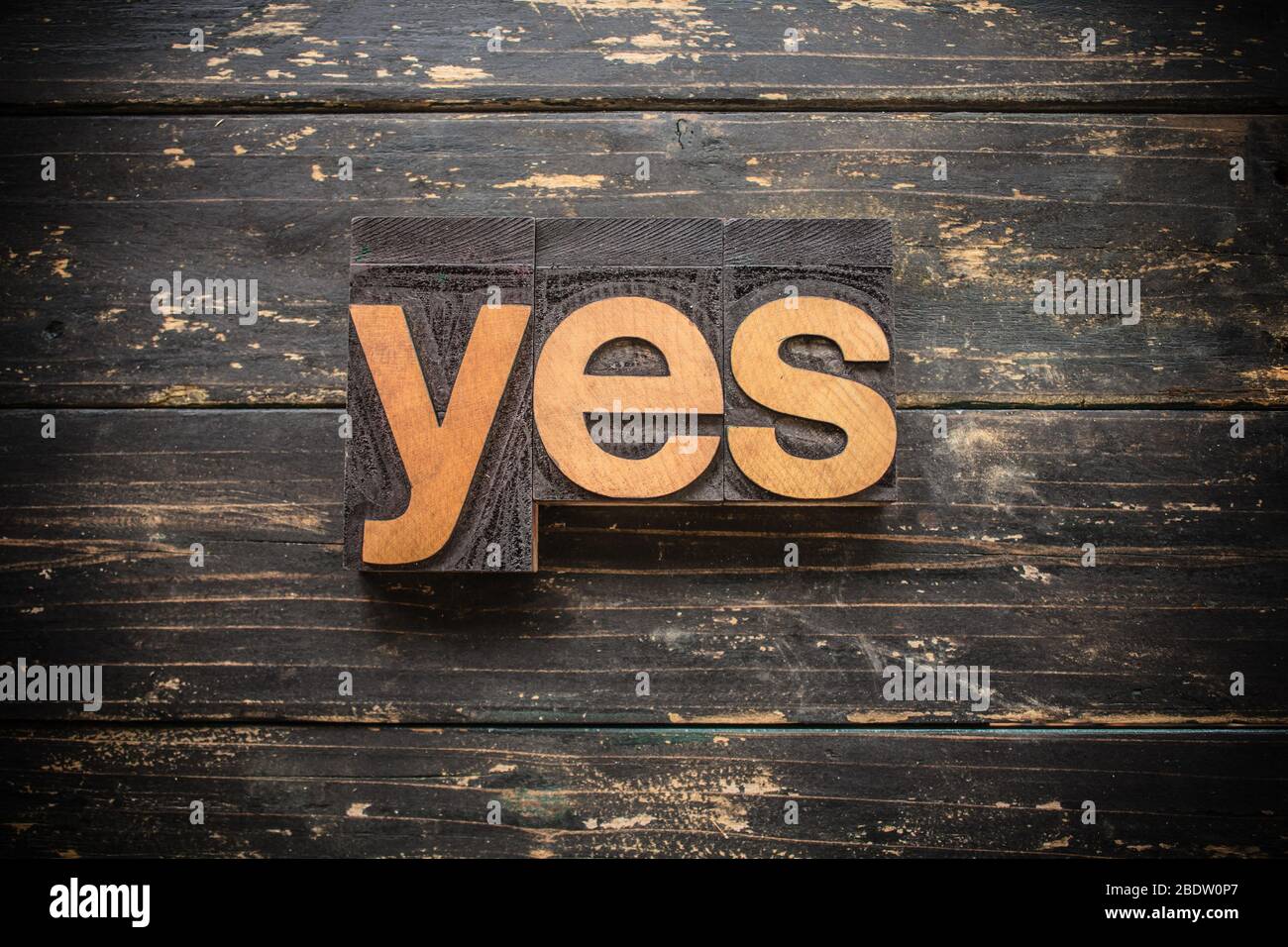 La palabra 'SÍ' escrito en madera vintage tipo tipografía sobre un fondo rústico vintage. Foto de stock