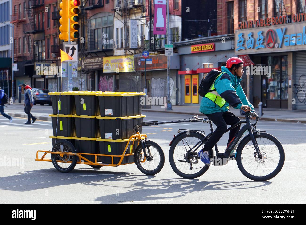 Nueva York, NY, 9 de abril de 2020. Un mensajero de la bicicleta parte de Whole Foods Market Bowery con una carga de comestibles... VEA MÁS INFORMACIÓN PARA VER EL TÍTULO COMPLETO Foto de stock