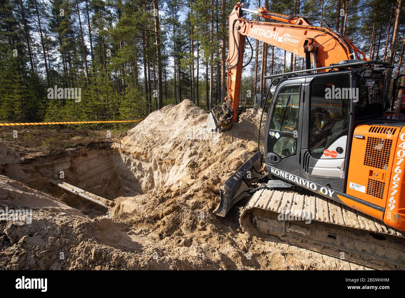 Naranja Hitachi digger y una zanja profunda en suelo arenoso, Finlandia Foto de stock