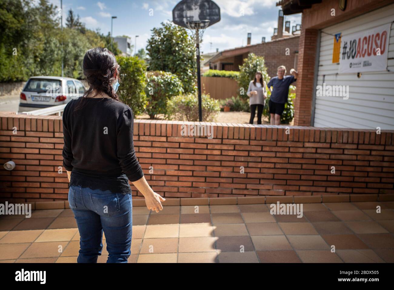 Mujer hablando con vecinos desde lejos durante el encierro de Covid19 en Cataluña, España Foto de stock