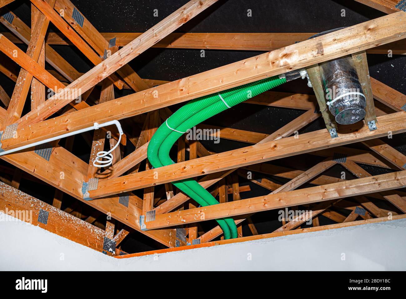 Ventilación de recuperación de energía doméstica, sistema visible de tubos flexibles verdes y difusor de suministro de aire, esparcidos por las cabezas de techo. Foto de stock