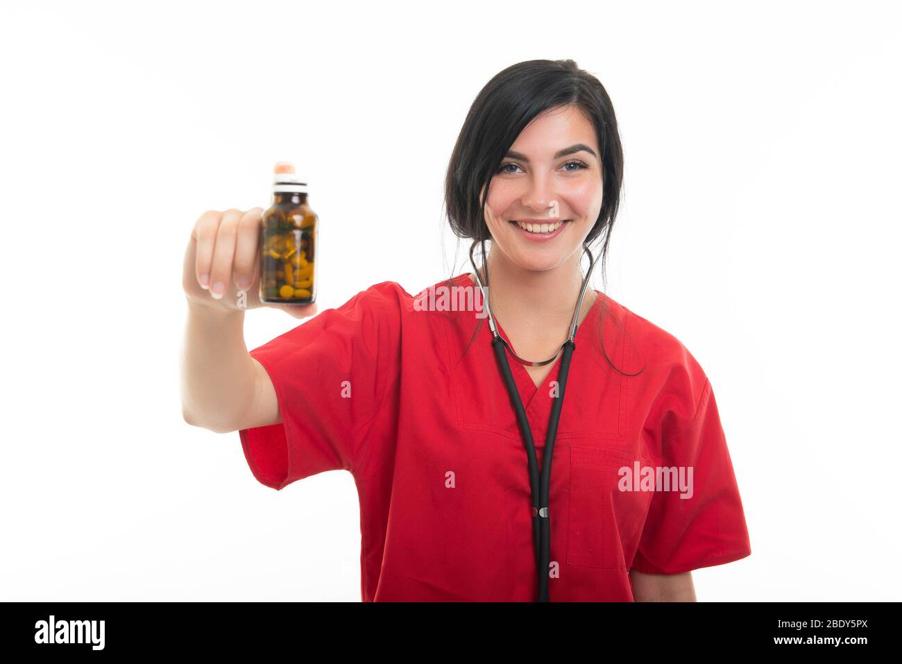 Retrato de una joven enfermera atractiva mostrando botella de píldoras aisladas sobre fondo blanco con área de publicidad del espacio de copia Foto de stock