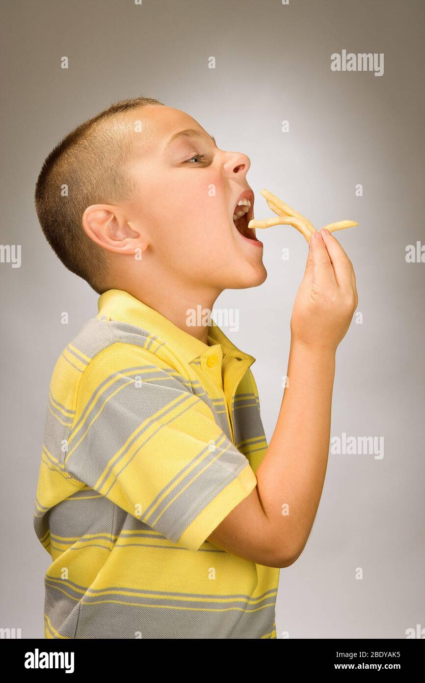 Niño comiendo patatas fritas Foto de stock