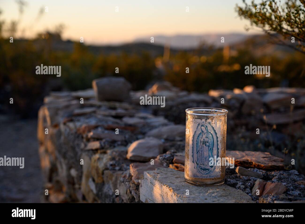 Una vela de oración católica se sienta junto a una tumba en el cementerio de Terlingua en el oeste de Texas, donde las tumbas están marcadas por adornos hechos a mano. Foto de stock