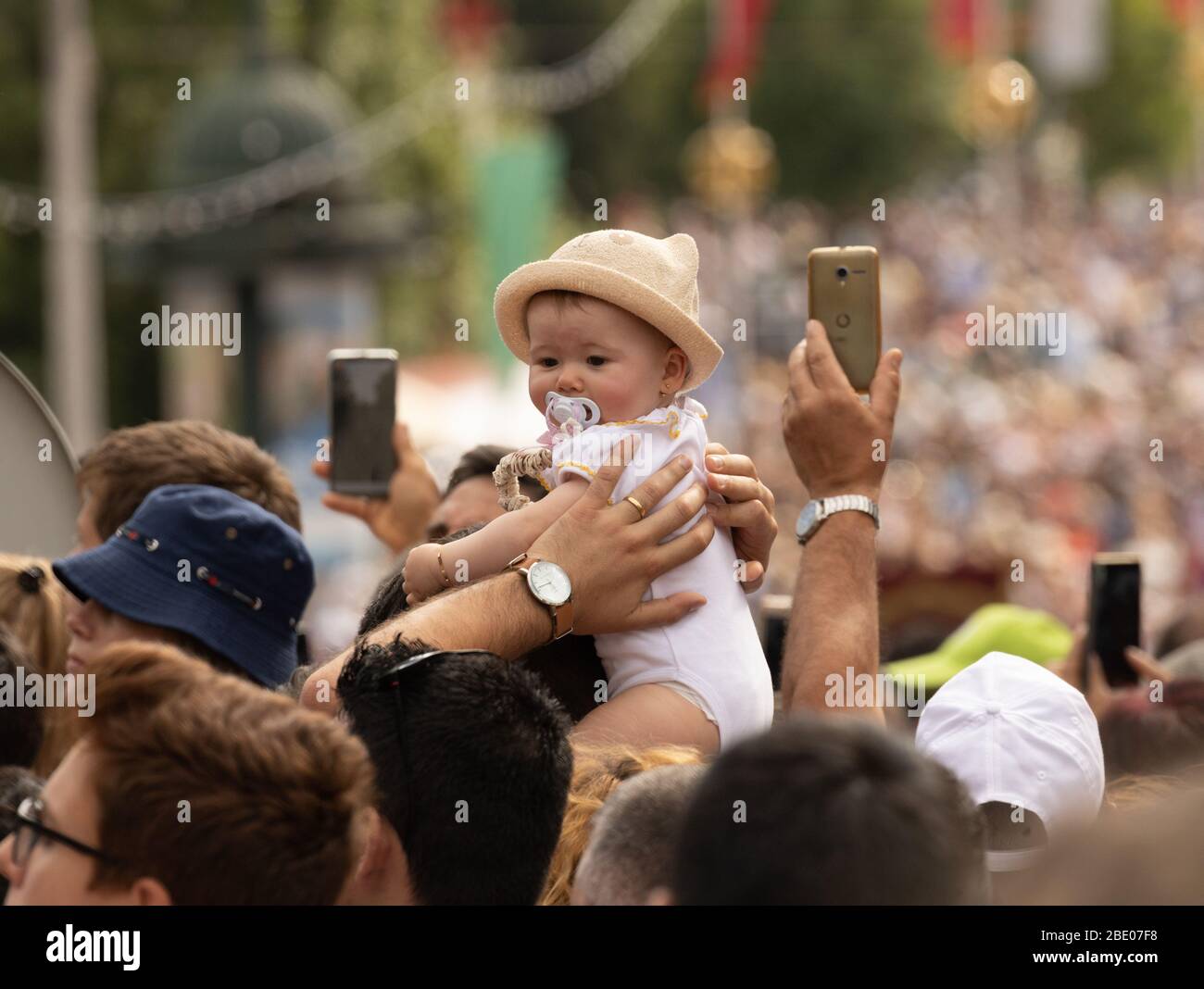 Bebé en medio de la multitud sostener alto y las manos tomando fotos con teléfonos durante el tradicional Festa dos Tabuleiros Festival de las bandejas tomar Portugal Foto de stock