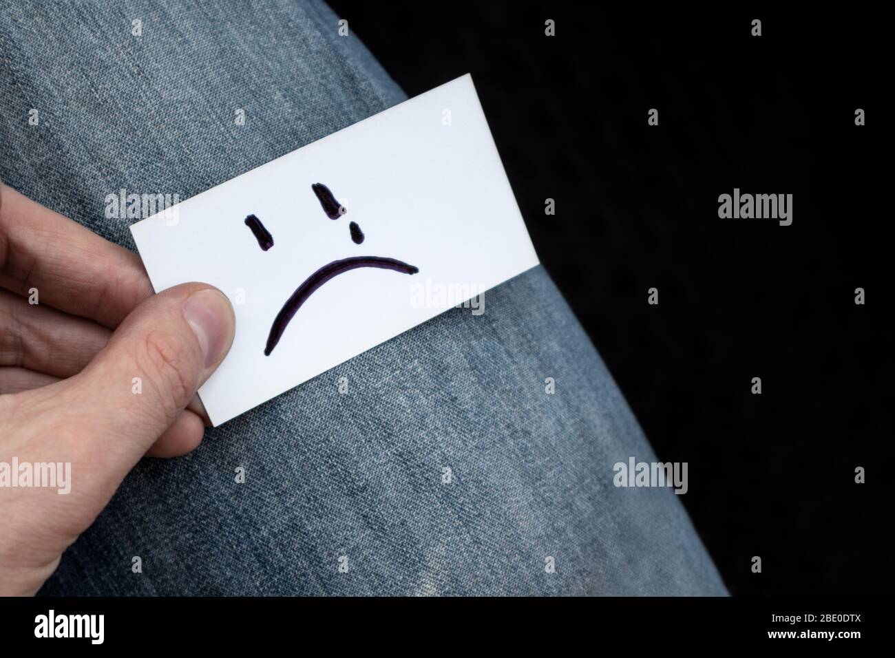 Rubí Proscrito Microprocesador Muy triste sonrisa emoji en papel blanco tarjeta de sostener en la mano  sobre vaqueros textura fondo. Estado de ánimo triste mal incoloro tiempo  Fotografía de stock - Alamy