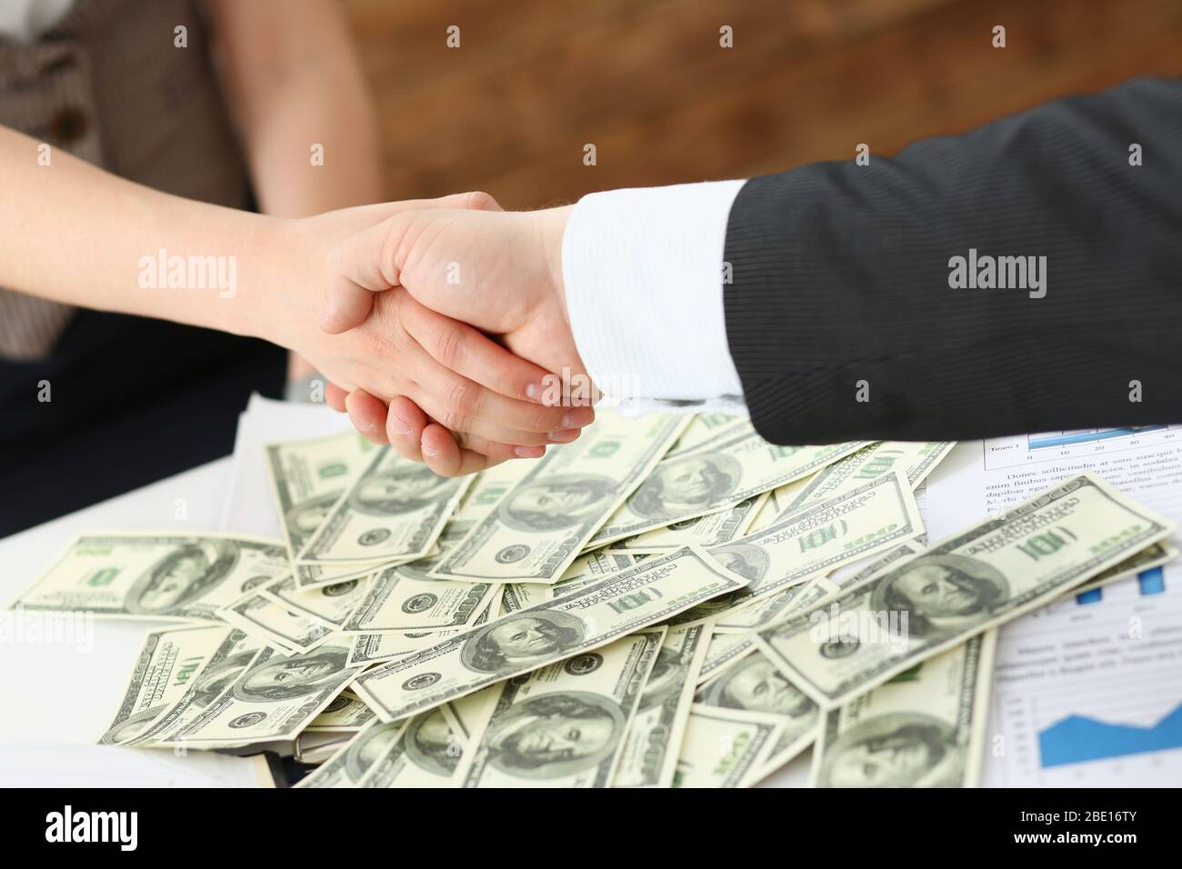 El hombre y la mujer se sacude las manos sobre la pila de dólares de transferencia de divisas de poderes Foto de stock