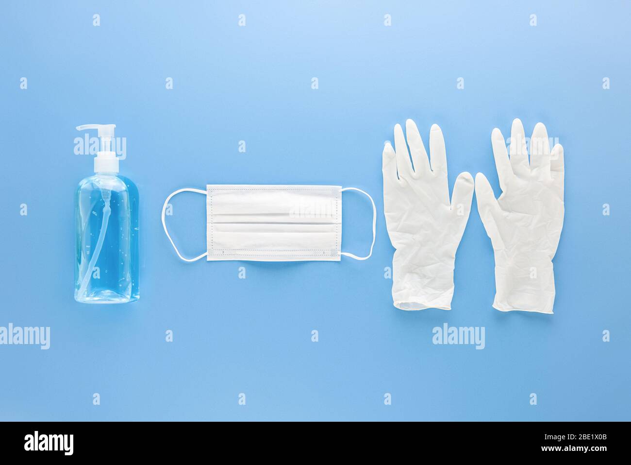 Mascarilla médica, guantes y desinfectante de manos de gel alcohal para proteger contra infecciones durante la pandemia de COVID-19 Foto de stock