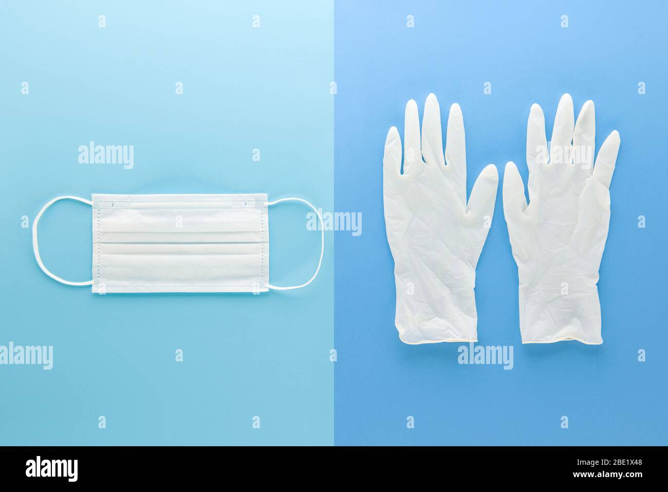 Máscara médica blanca y guantes de goma limpios para protección durante la pandemia de Coronavirus vista superior sobre fondo azul claro Foto de stock