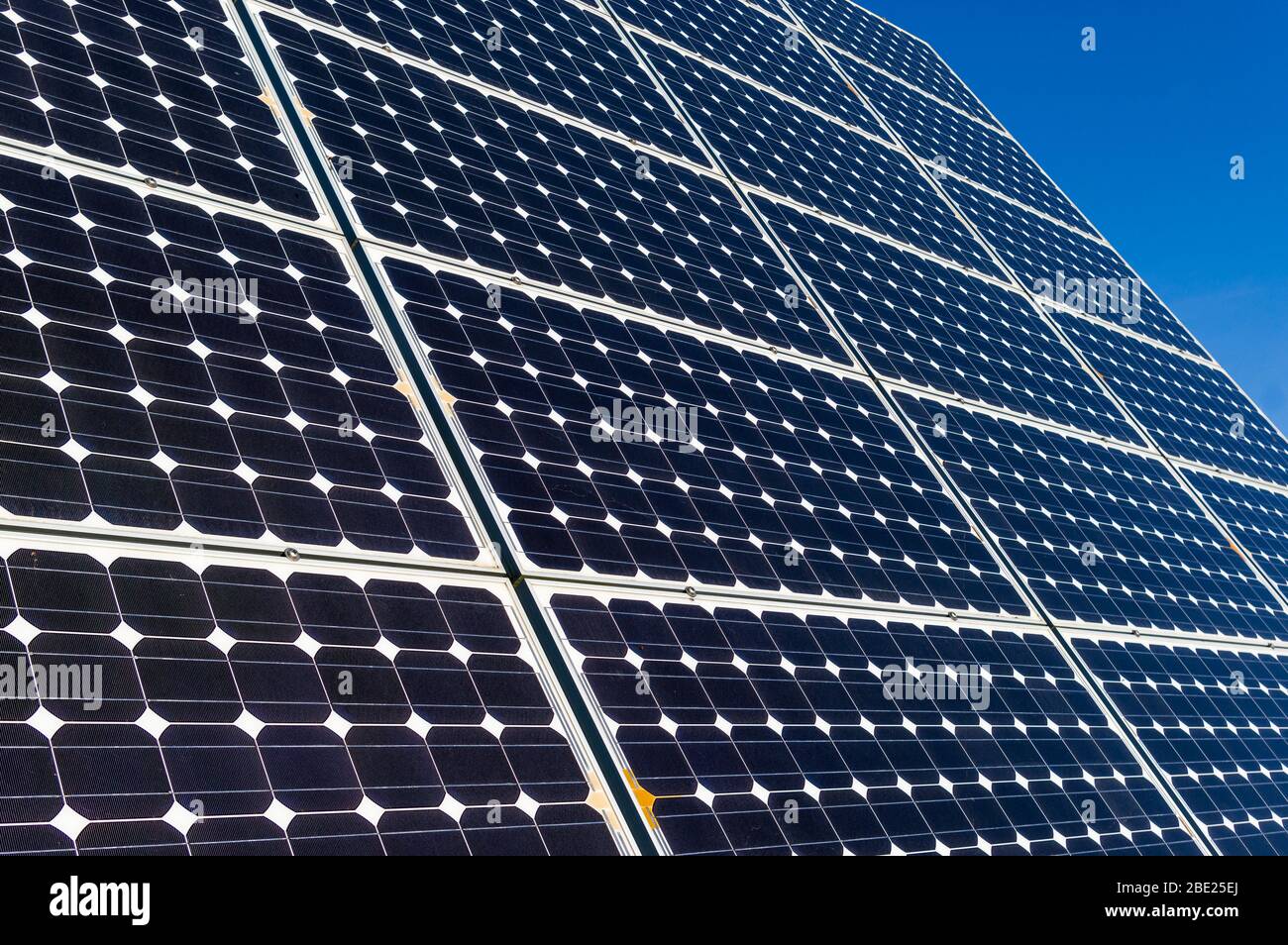 Primer plano, vista detallada de los paneles solares de una planta de energía solar en un cielo azul brillante y sin nubes Foto de stock