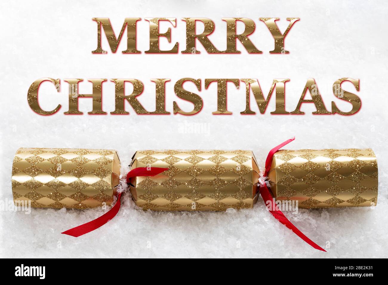 Feliz mensaje de Navidad con un cracker dorado de Navidad y un fondo de nieve Foto de stock