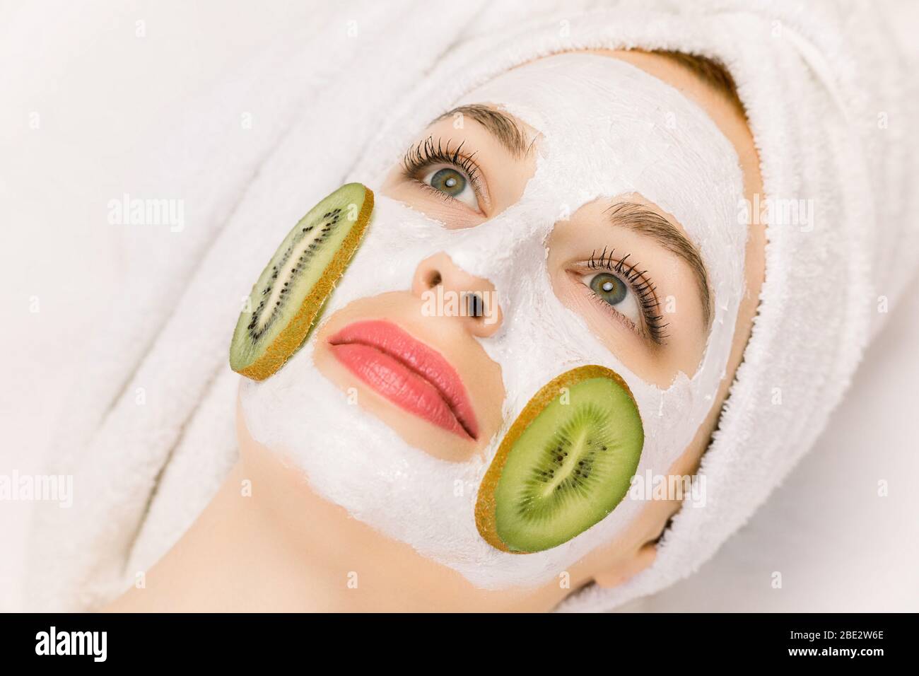Mascarilla facial con frutas, tratamiento de belleza en el spa, cuidado de  la piel. Bonita chica con máscara de kiwi en la cara, y rodajas de kiwi en  sus mejillas, y el