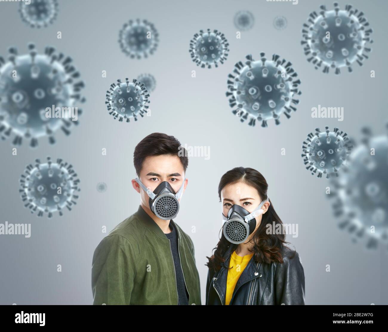 Una joven pareja asiática que lleva máscaras de gas mirando la cámara mostrando miedo en una época de crisis pandémica global de COVID-19 Foto de stock