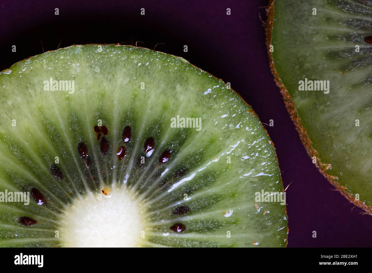 un fantástico estudio de fotografía de primer plano con detalles de vida natural de deliciosas frutas kiwi en rodajas sobre plato púrpura, vista superior Foto de stock