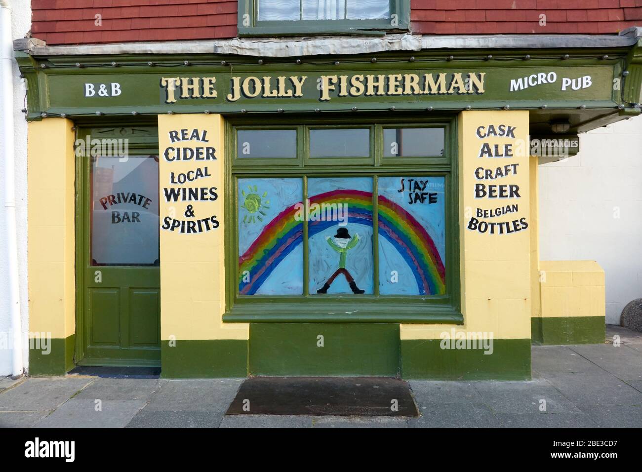 El pub Jolly Fisherman en Hastings, cerrado durante el cierre del coronavirus, mostrando un arco iris pintado en solidaridad, con un mensaje para permanecer seguro Foto de stock
