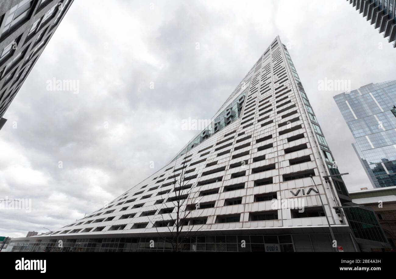 Un edificio arquitectónicamente impresionante en w 57th St. Cerca de los muelles parece doblarse hacia adentro. Las oscuras nubes en un día nublado dan una sensación ominosa Foto de stock