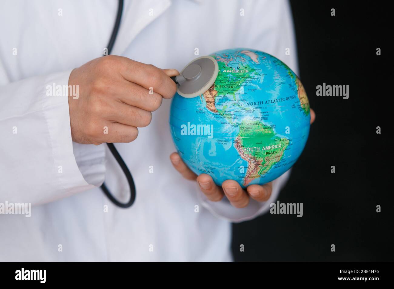 Un médico con estetoscopio ausculta la respiración de los pulmones del planeta Tierra - neumonía y coronavirus en los EE.UU. - diagnóstico médico Foto de stock