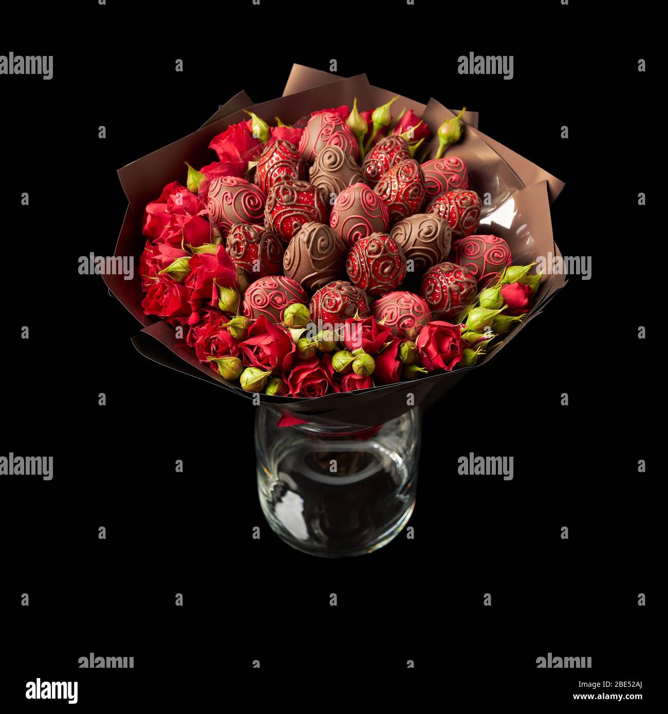 Hermoso ramo de rosas rojas y fresas maduras en chocolate envuelto en papel  marrón sobre fondo negro Fotografía de stock - Alamy