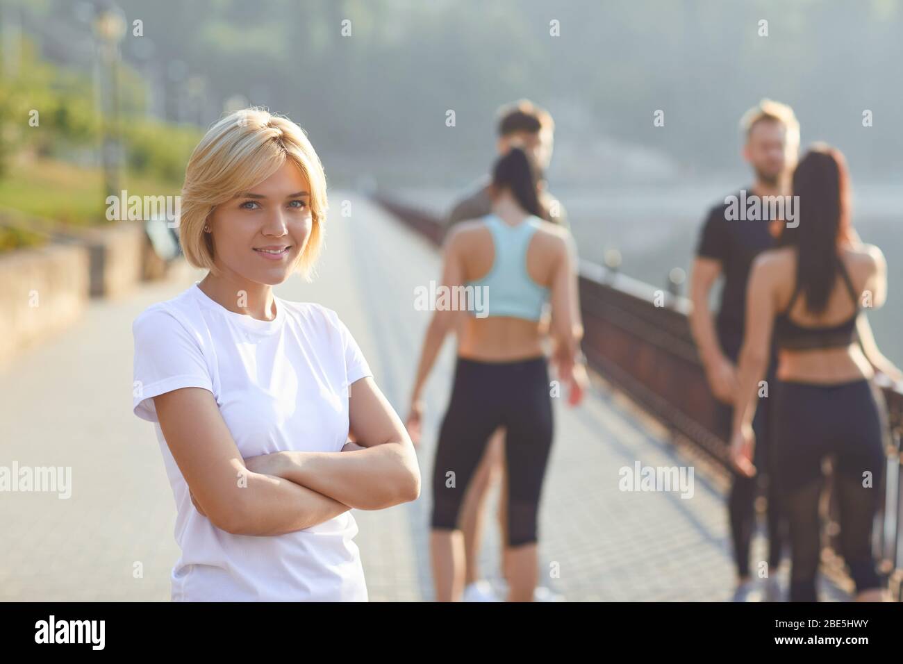 Chica deportiva sonrisas en el fondo de amigos atletas en el parque Foto de stock