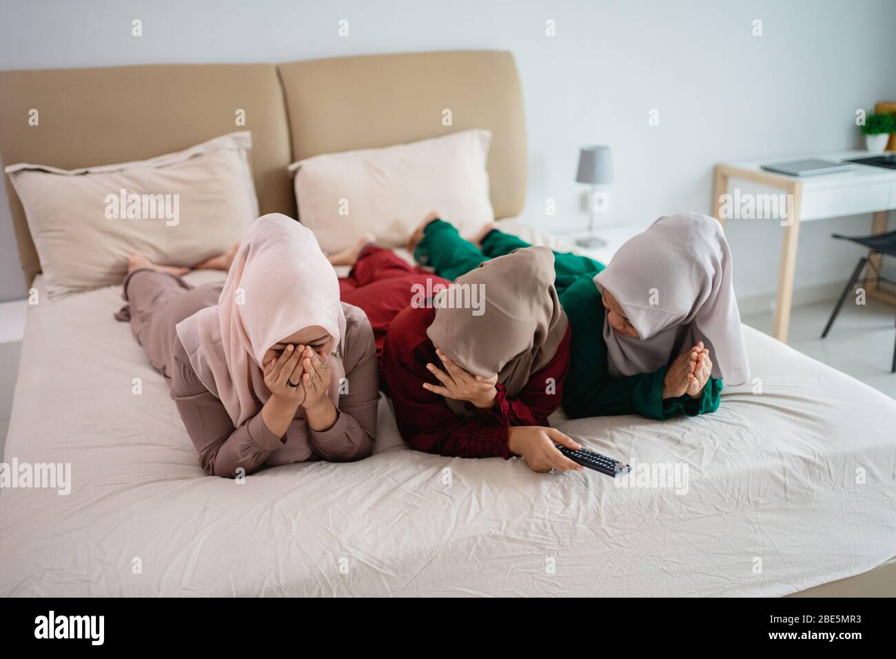 tres mujeres veladas acostadas en la cama y asustan cuando ven la  televisión para pasar el tiempo juntos Fotografía de stock - Alamy