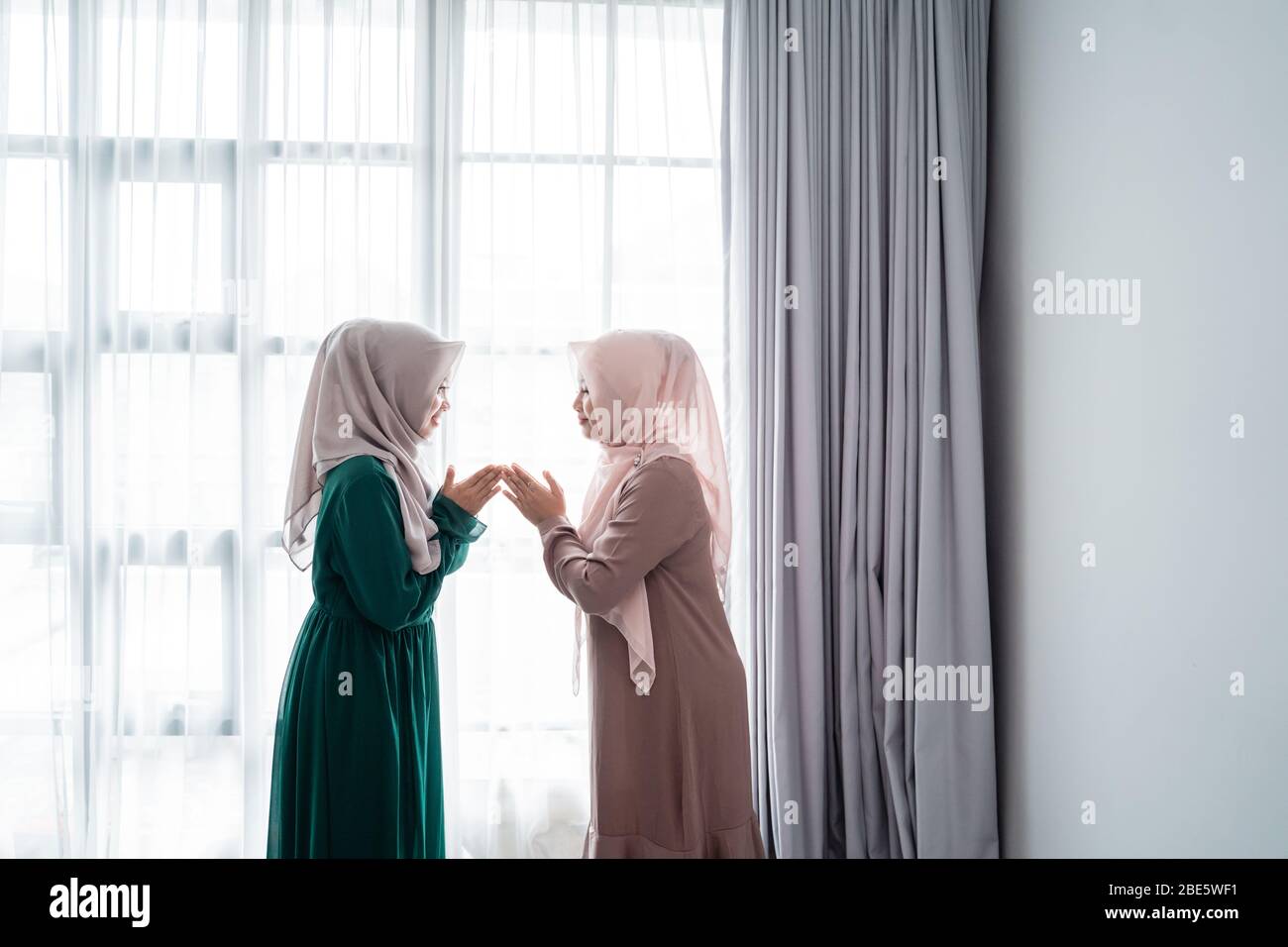 la mujer lleva hijab decir salam cuando se encuentra con su amigo cuando ella entra a través de la puerta Foto de stock
