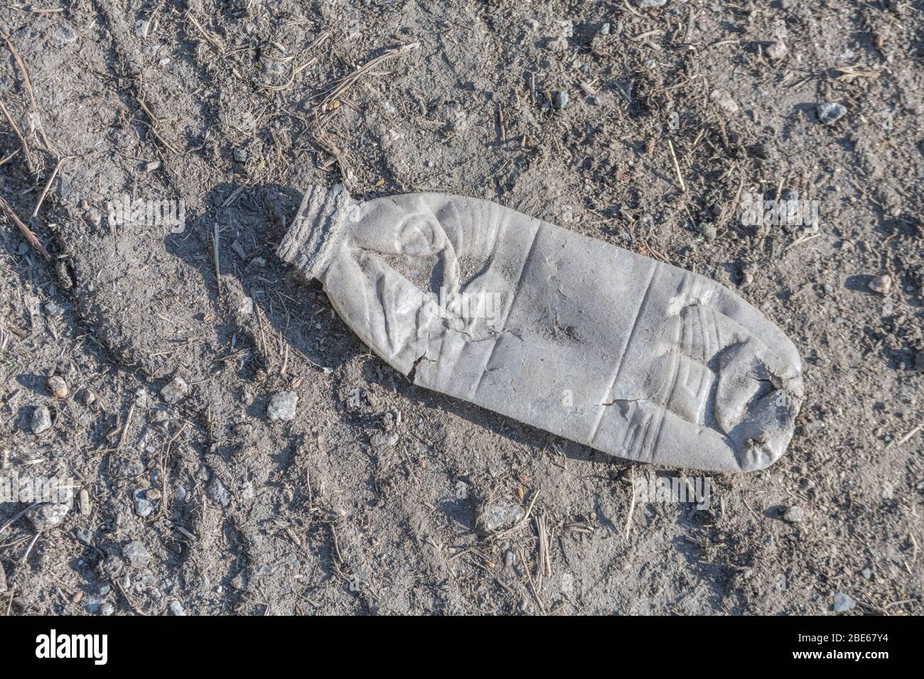 Vacíe la botella de refrescos en el asfalto de una tranquila carretera
