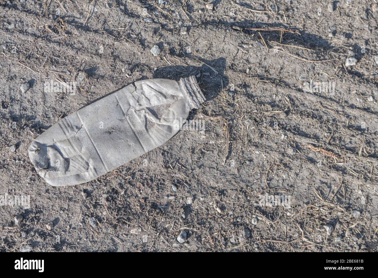 Vacíe la botella de refrescos en el asfalto de una tranquila carretera