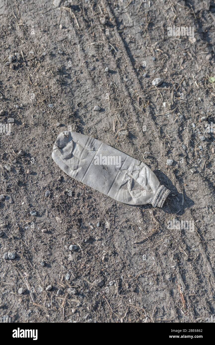 Botella de refrescos vacía en asfalto de carretera rural tranquila