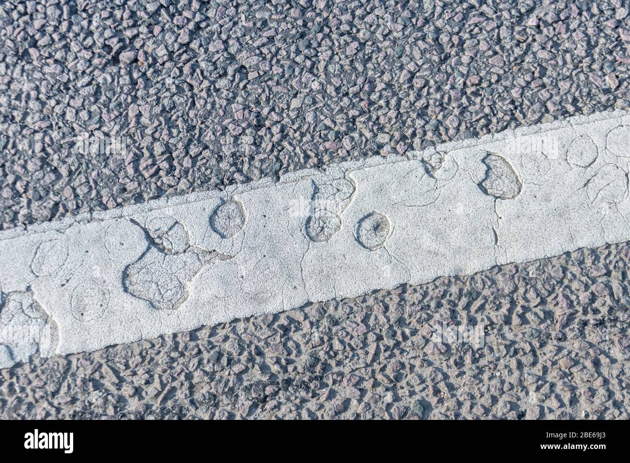 Patrón abstracto punteado en pintura blanca de la Marca de carreteras del Reino Unido. Textura de pintura antigua, formas abstractas, agujeros abstractos, agujeros redondos, concepto de transporte por carretera. Foto de stock