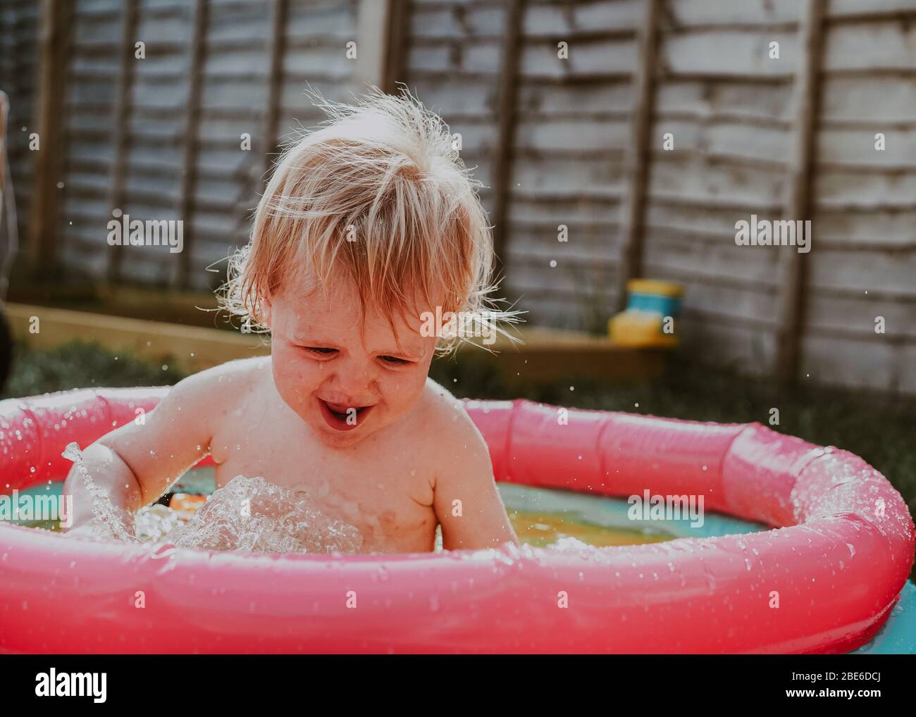 Pequeño robot niño jugando en la piscina infantil en el jardín en verano, Reino Unido Foto de stock