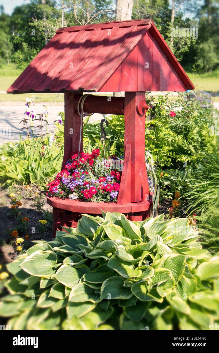 Un pozo de agua ornamental en medio de un jardín comunitario. Vegetación y  flores Fotografía de stock - Alamy