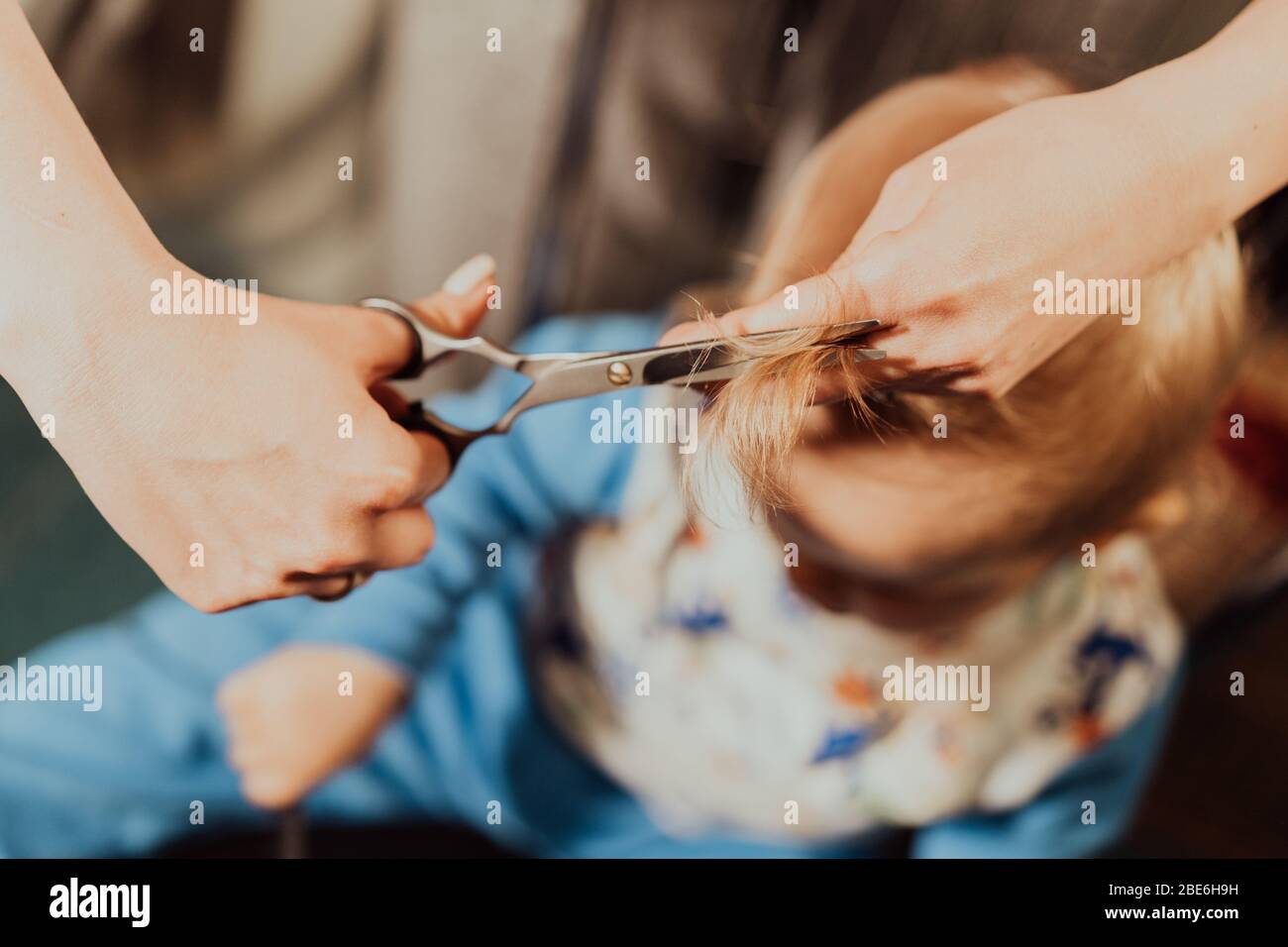 Primer corte de pelo de niño pequeño en casa por los padres. Retrato en blanco y negro. Foto de stock