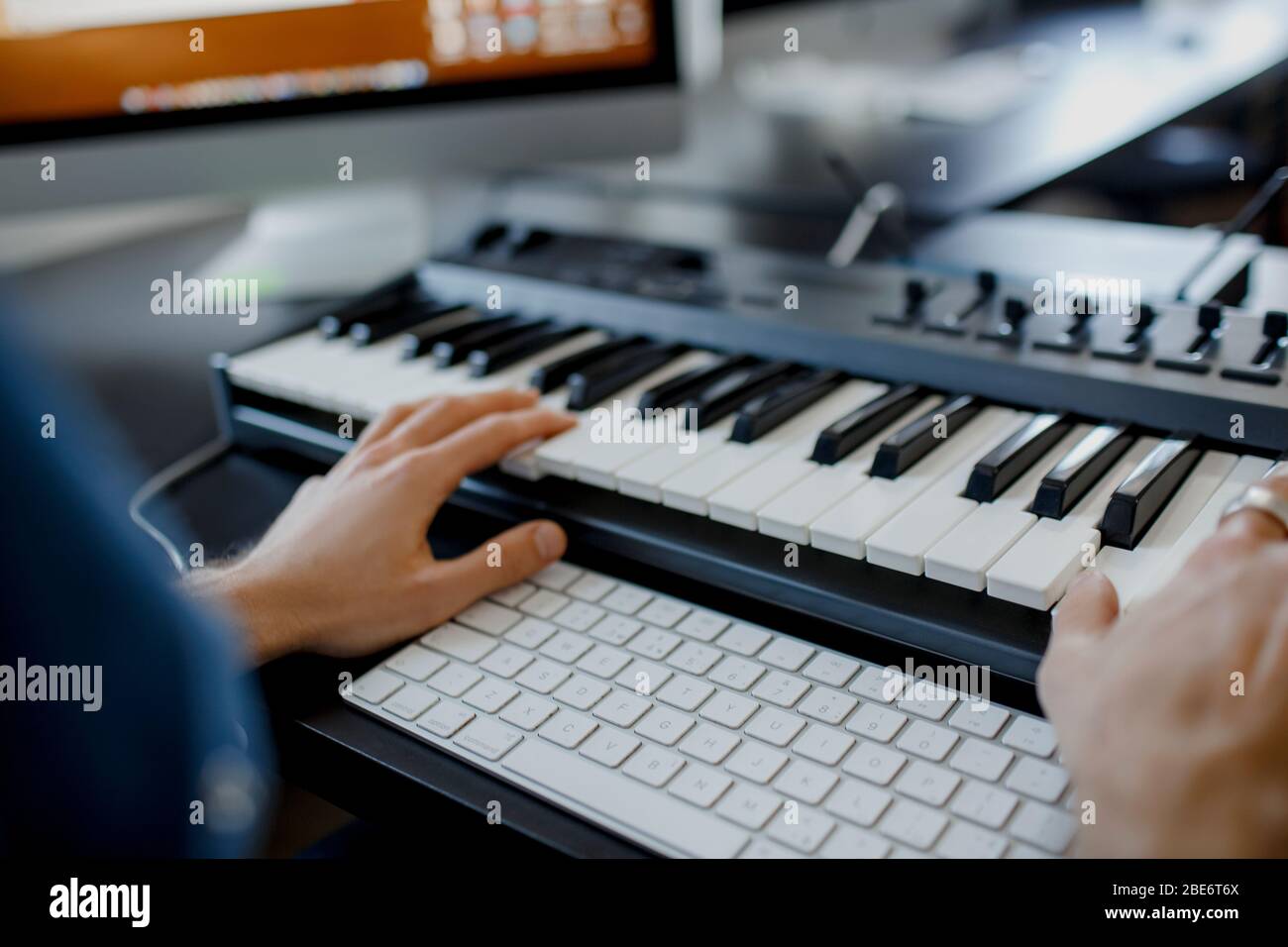 composer tiene las teclas de piano en el estudio de grabación. tecnología  de producción musical, el hombre está trabajando en pianino y el teclado  del ordenador en el escritorio. primer plano Fotografía