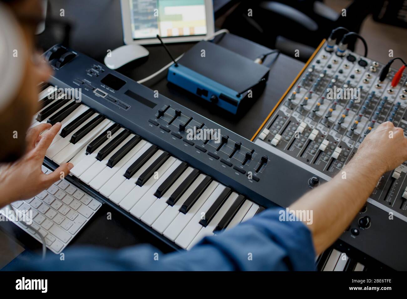 composer tiene las teclas de piano en el estudio de grabación. tecnología  de producción musical, el hombre está trabajando en pianino y el teclado  del ordenador en el escritorio. primer plano Fotografía