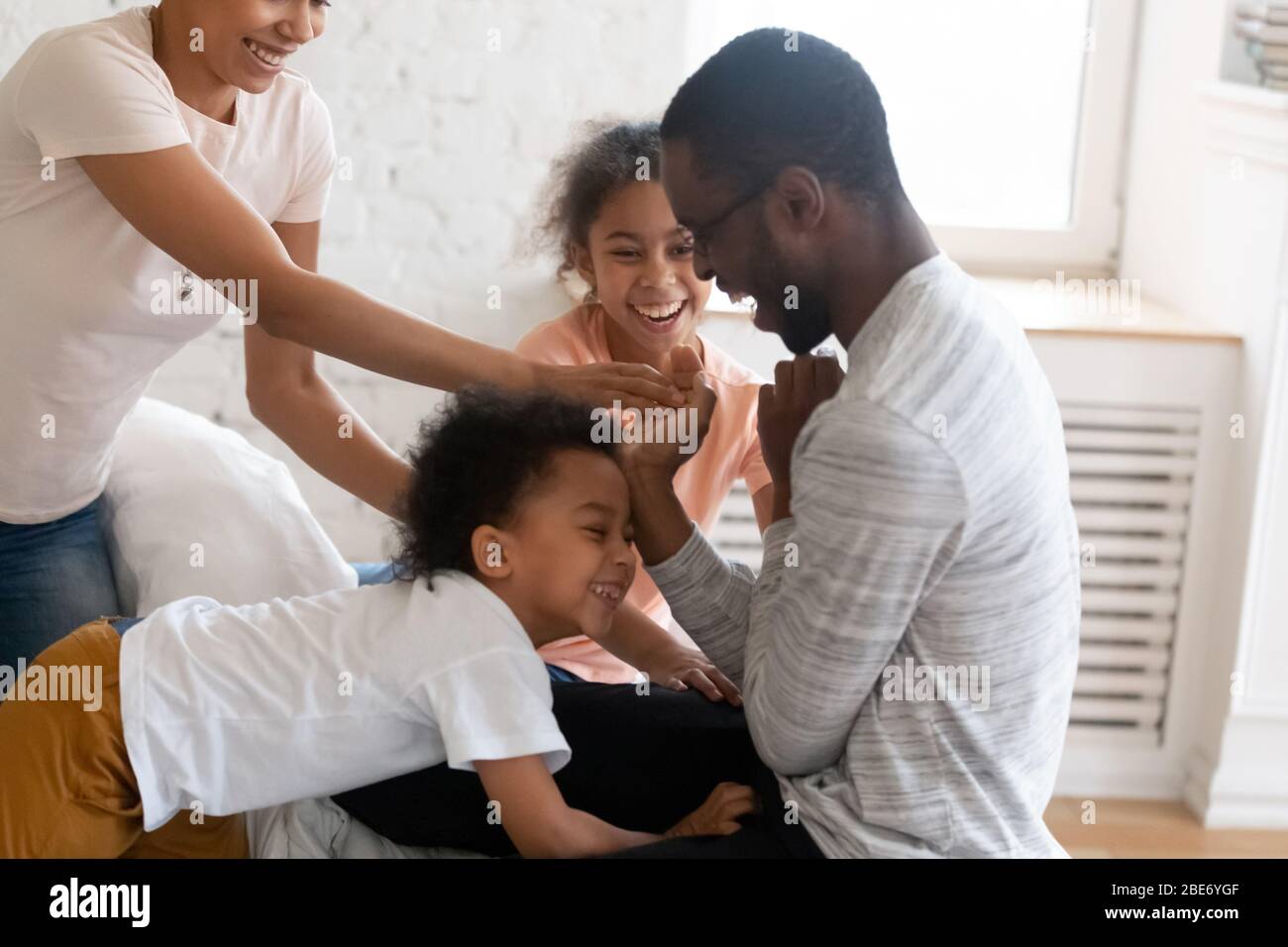 Feliz familia afroamericana cosquillear a los niños y pasar un buen rato. Foto de stock