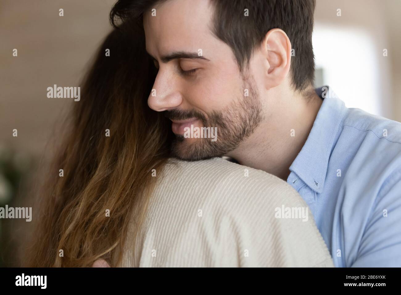 Joven barbudo abrazando a esposa después de reconciliar. Foto de stock