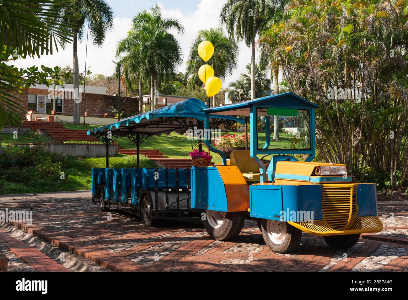 tren turístico, azul y amarillo en un parque listo para ir sin gente en un hermoso parque Foto de stock