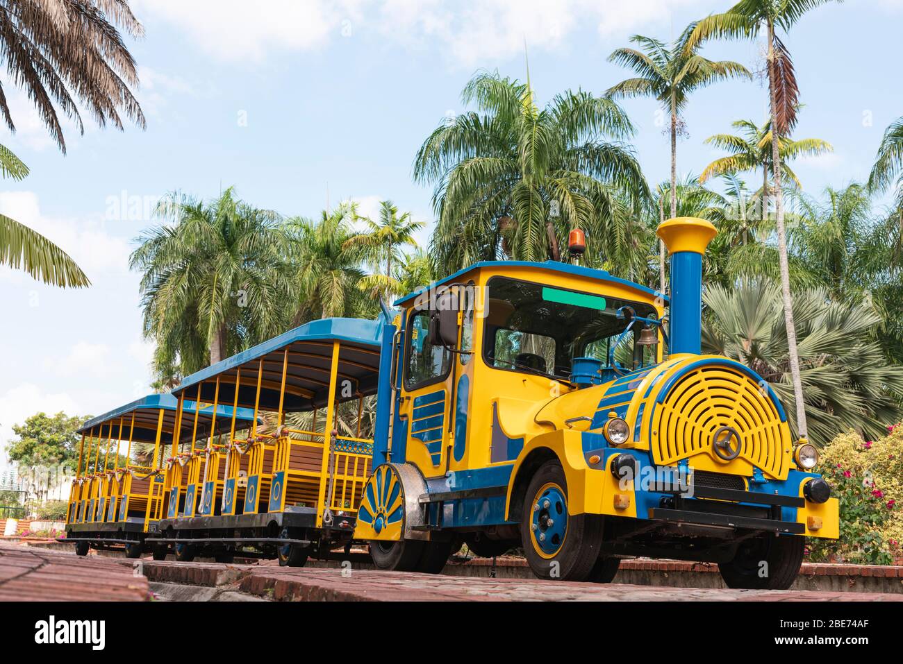 tren turístico, azul y amarillo en un parque listo para ir sin gente en un hermoso parque Foto de stock