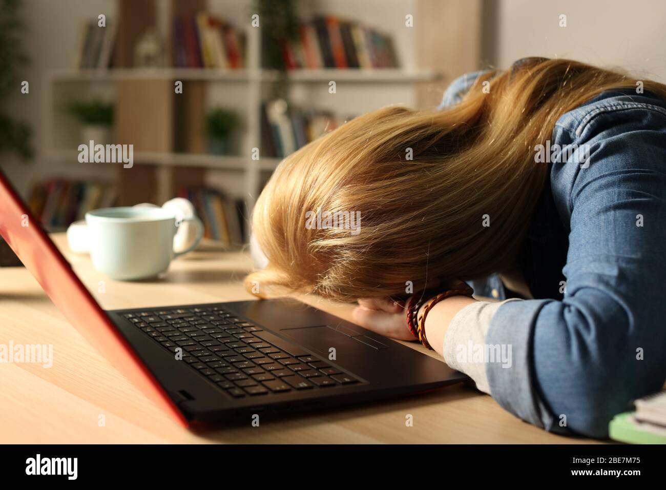 Primer plano de una estudiante cansada y sobrecargada con un portátil durmiendo por la noche sobre el escritorio en casa Foto de stock