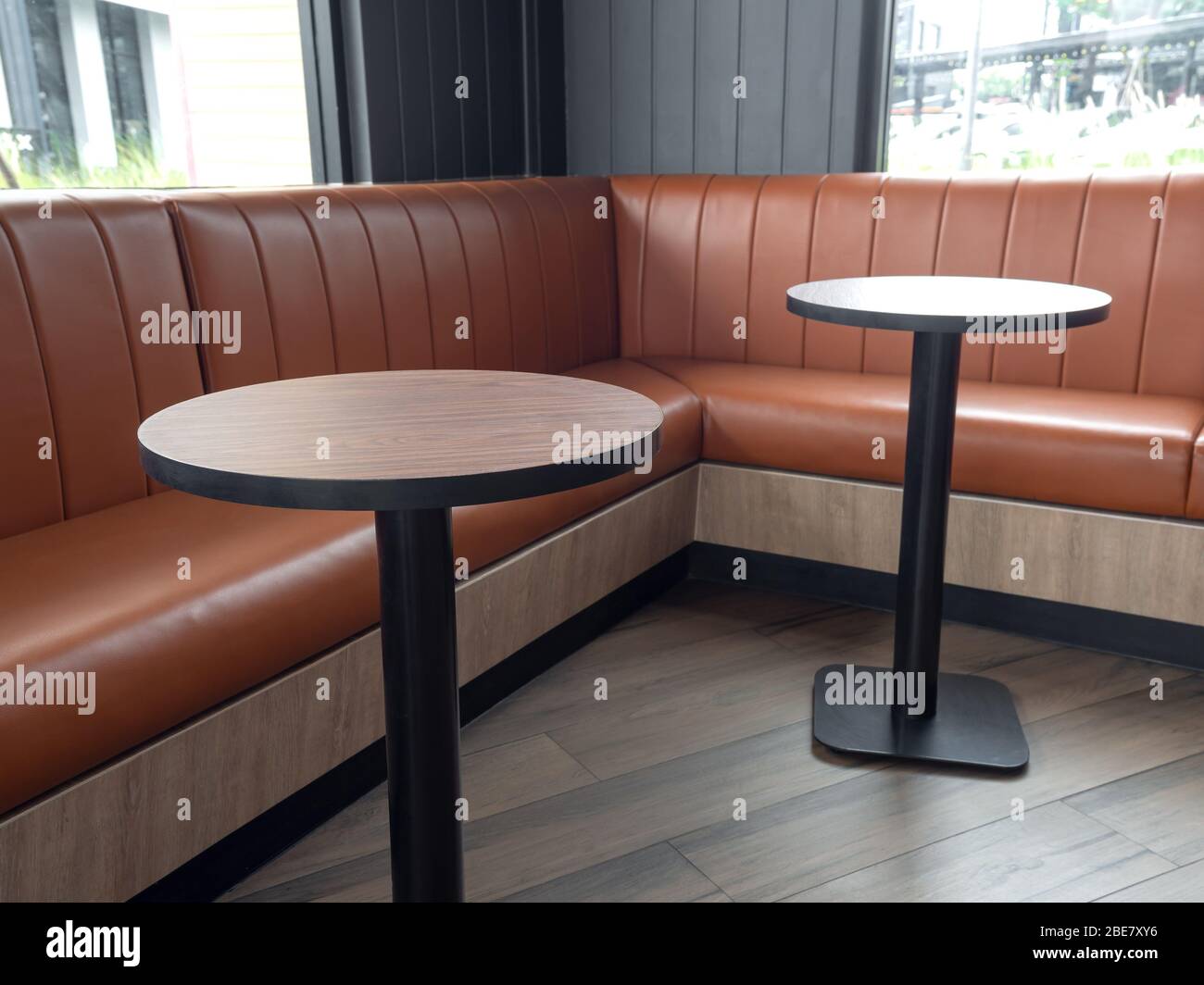 Decoración de muebles en estilo café retro. Mesas redondas vacías de madera  y sofá de cuero naranja en el suelo de madera con luz natural Fotografía de  stock - Alamy
